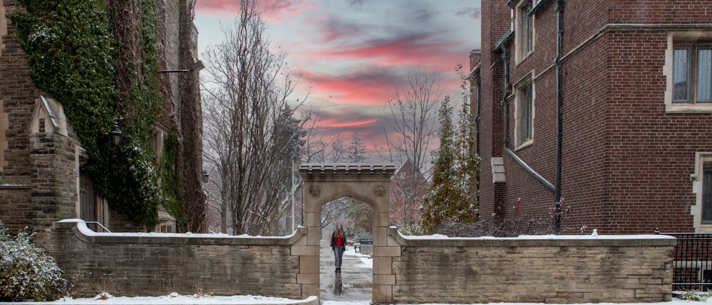 McMaster student walking through the arch at sunset