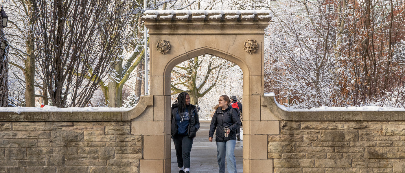 Two students walking through Edwards Arch in the winter on the McMaster campus.